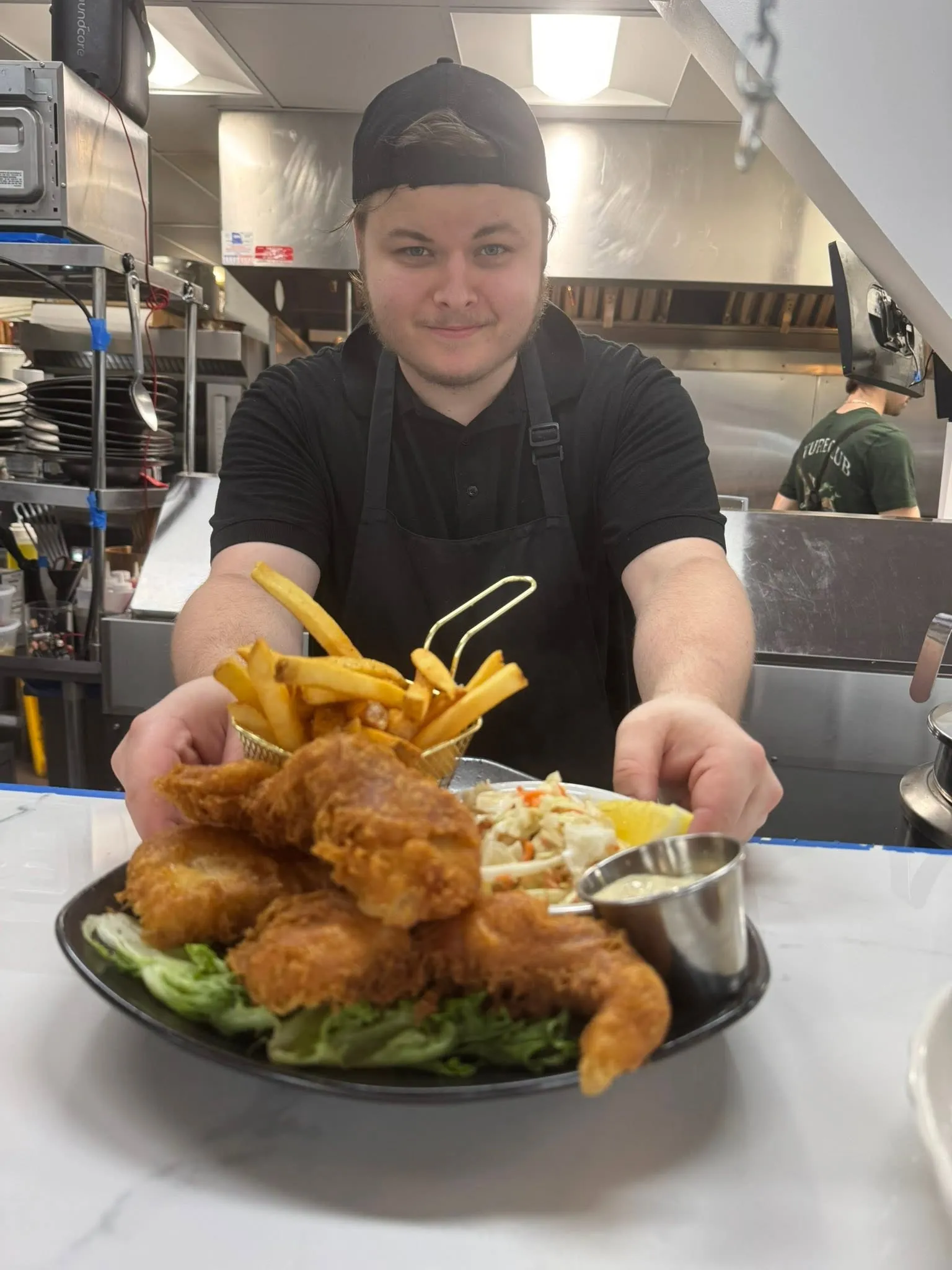 One of our cooks handing a plate of fish and chips across the counter