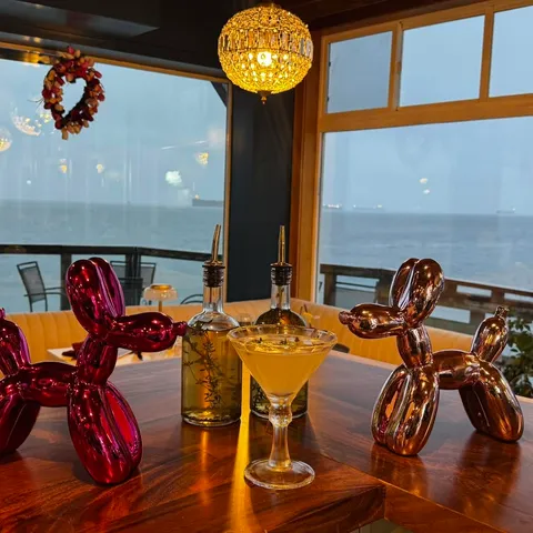 A cocktail on a window table at dusk, the river outside
